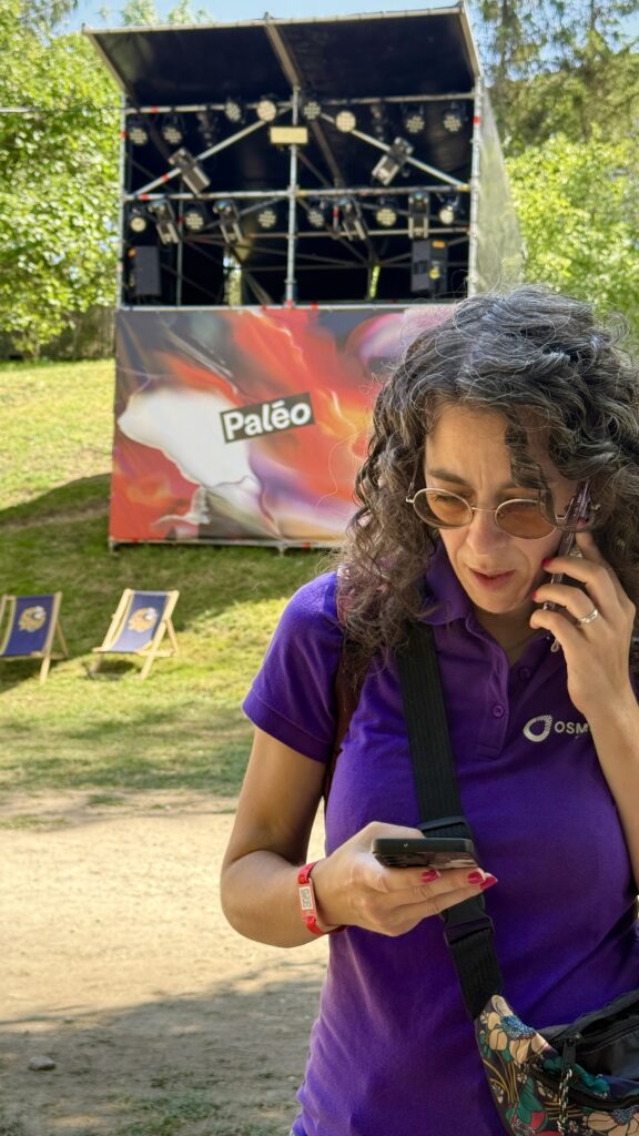 Noémie Mezenen, d'Osmose Marketing, au téléphone devant une scène du Paléo Festival