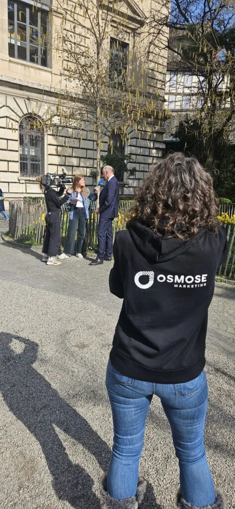 Collaboratrice d'Osmose Marketing en veste de l'agence lors d'un reportage devant un bâtiment officiel