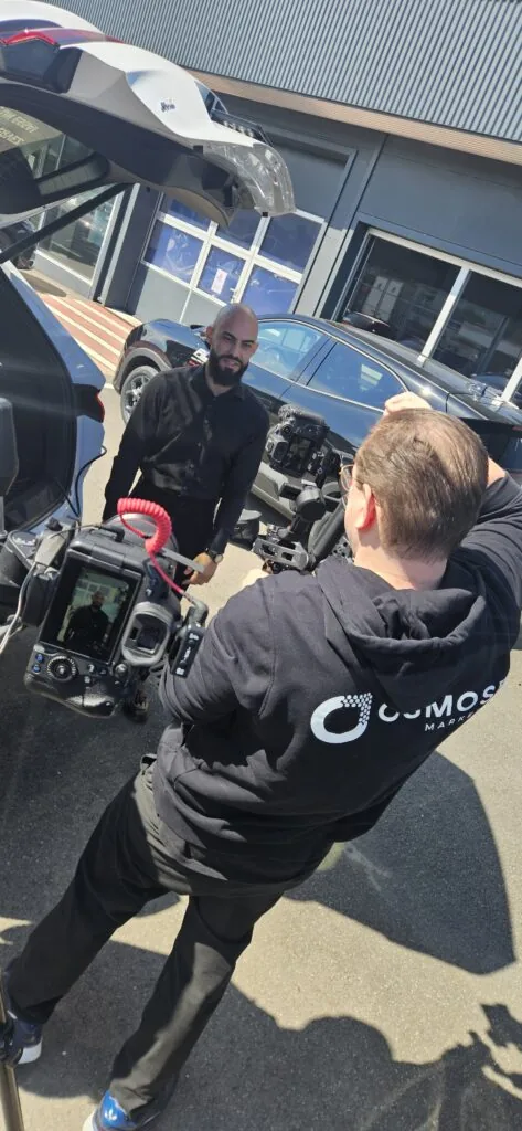 Deux collaborateurs d'Osmose Marketing filment en extérieur devant des véhicules