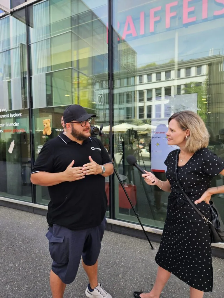Interview filmée par Osmose Marketing devant une agence Raiffeisen, perche micro à la main
